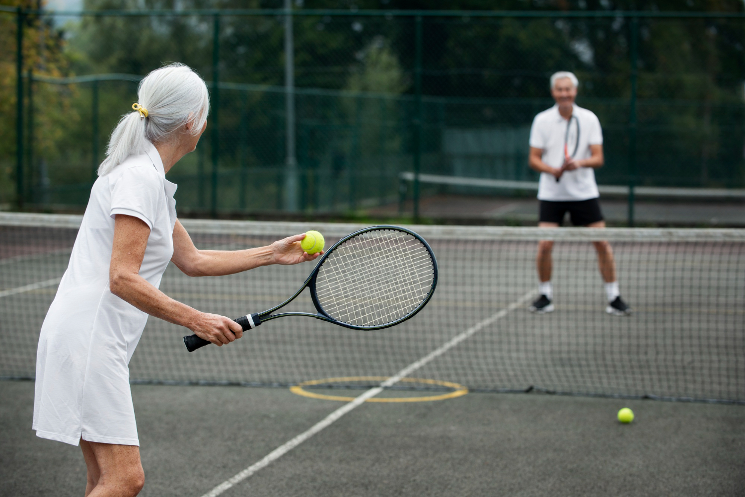 Vrouw in witte sportkleding heeft geen last van een tennisarm.