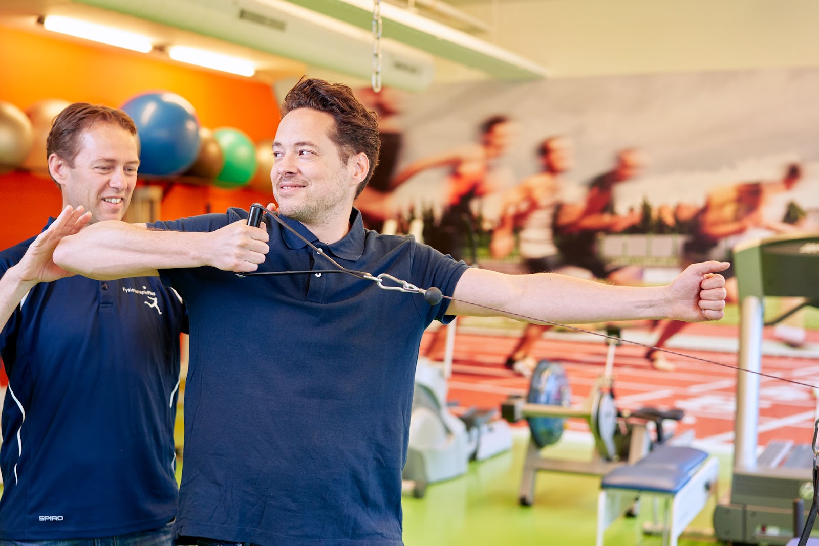 Man wordt geholpen na zijn schouderoperatie door een fysiotherapeut in een blauw shirt